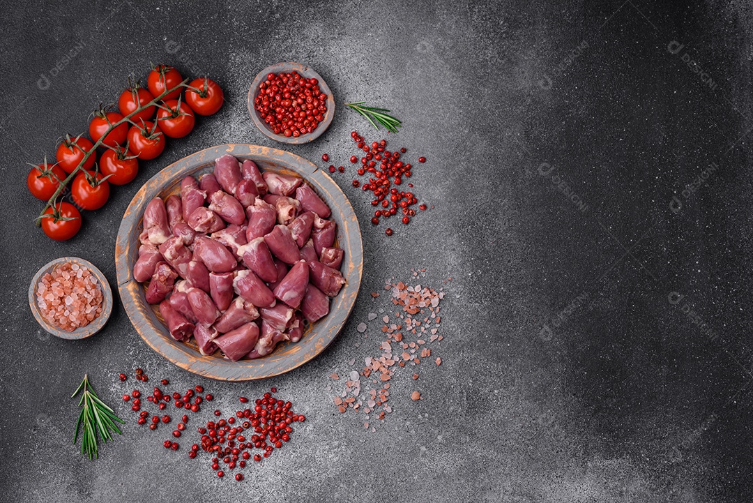 Corações crus de frango ou peru com sal, especiarias e ervas sobre um fundo de concreto texturizado