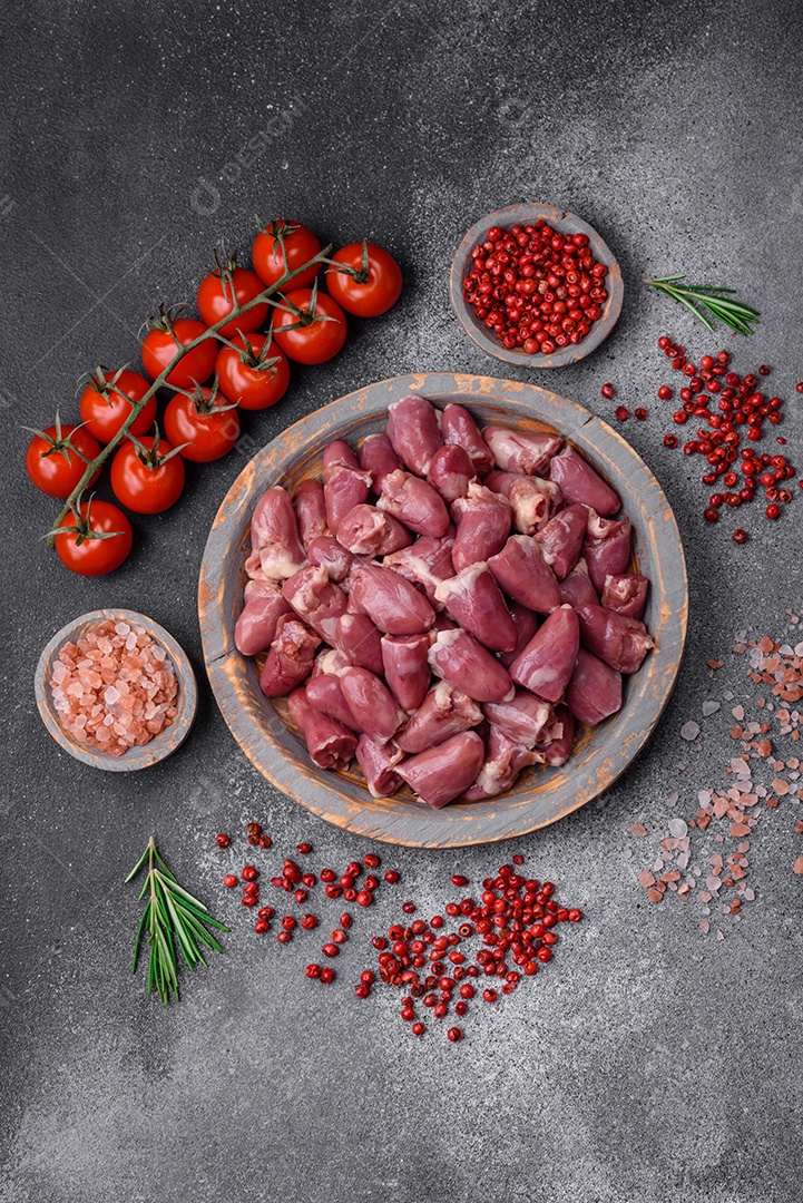 Corações crus de frango ou peru com sal, especiarias e ervas sobre um fundo de concreto texturizado