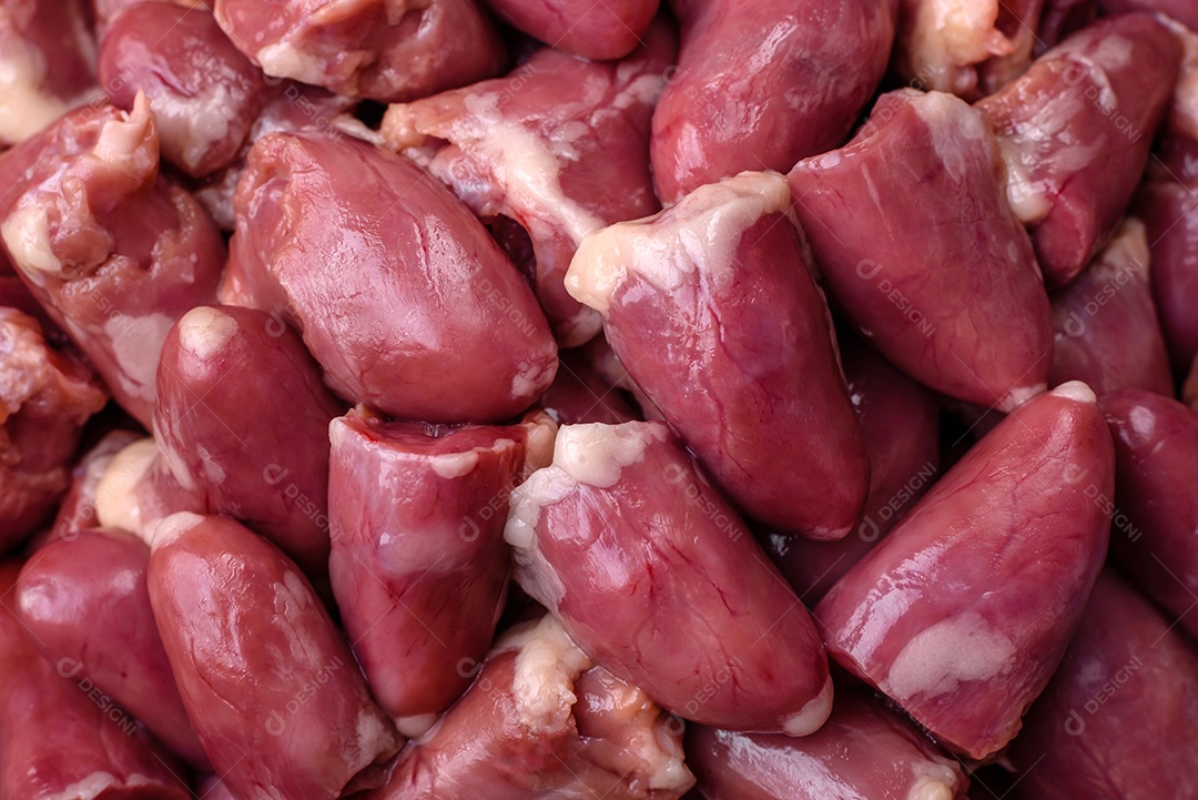 Corações crus de frango ou peru com sal, especiarias e ervas sobre um fundo de concreto texturizado