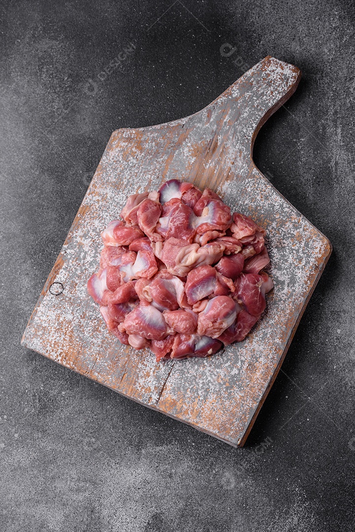 Corações crus de frango ou peru com sal, especiarias e ervas sobre um fundo de concreto texturizado