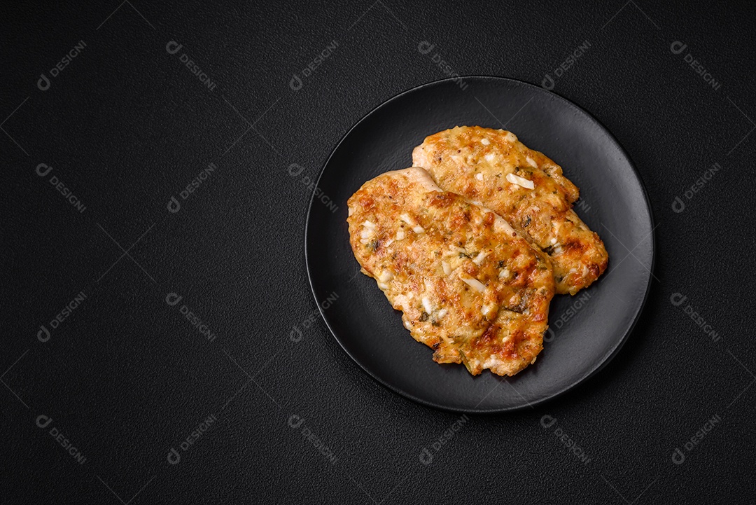 Delicioso peito de frango frito em massa com mostarda, sal, especiarias e queijo sobre fundo escuro de concreto