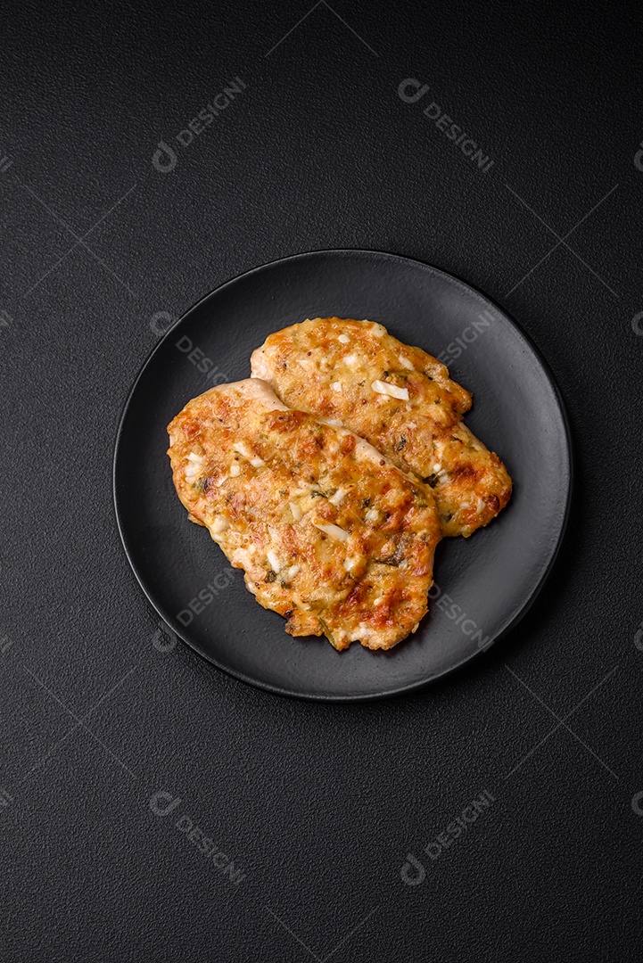 Delicioso peito de frango frito em massa com mostarda, sal, especiarias e queijo sobre fundo escuro de concreto