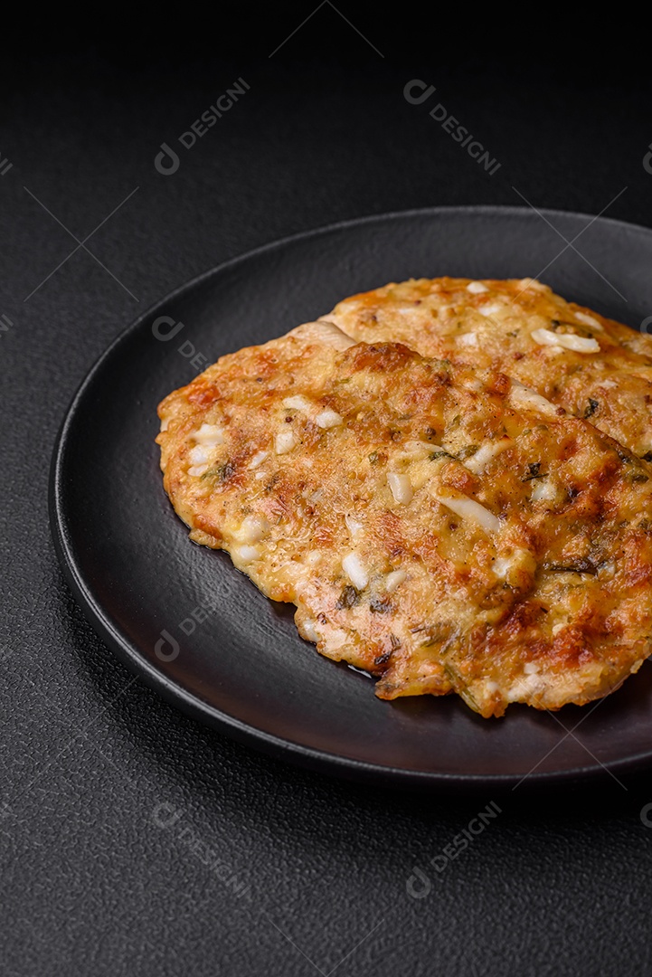 Delicioso peito de frango frito em massa com mostarda, sal, especiarias e queijo sobre fundo escuro de concreto