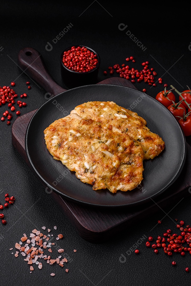 Delicioso peito de frango frito em massa com mostarda, sal, especiarias e queijo sobre fundo escuro de concreto