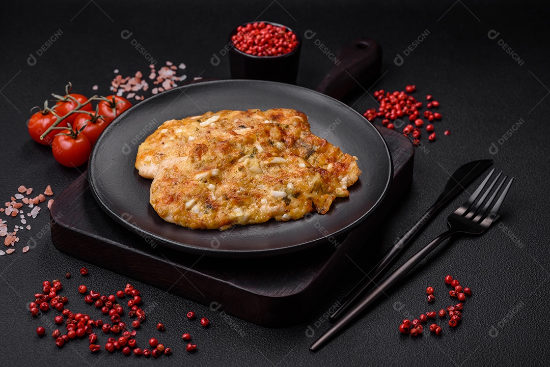 Delicioso peito de frango frito em massa com mostarda, sal, especiarias e queijo sobre fundo escuro de concreto