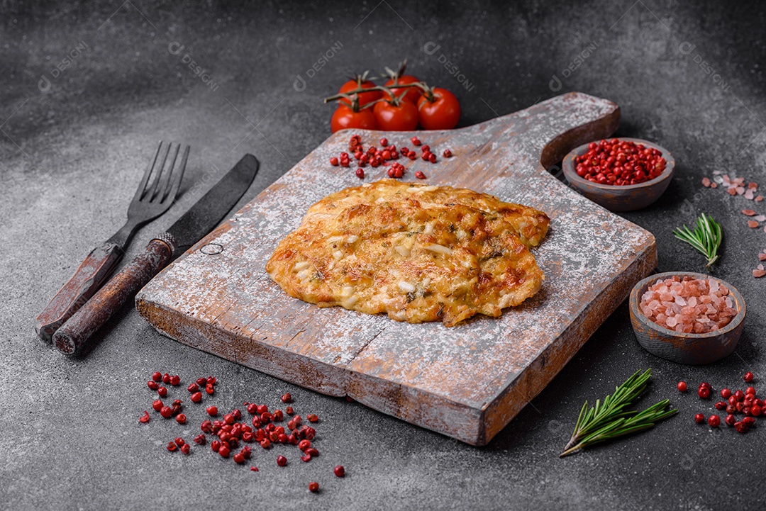 Delicioso peito de frango frito em massa com mostarda, sal, especiarias e queijo sobre fundo escuro de concreto