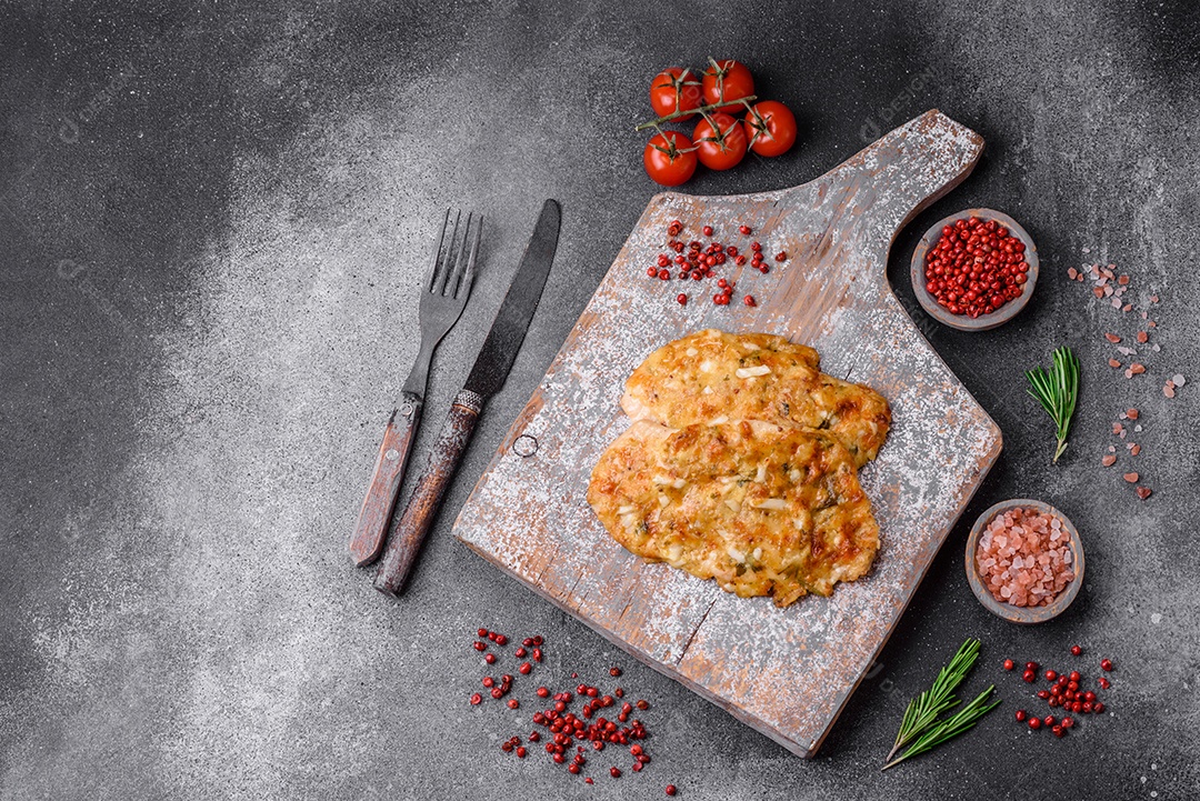Delicioso peito de frango frito em massa com mostarda, sal, especiarias e queijo sobre fundo escuro de concreto