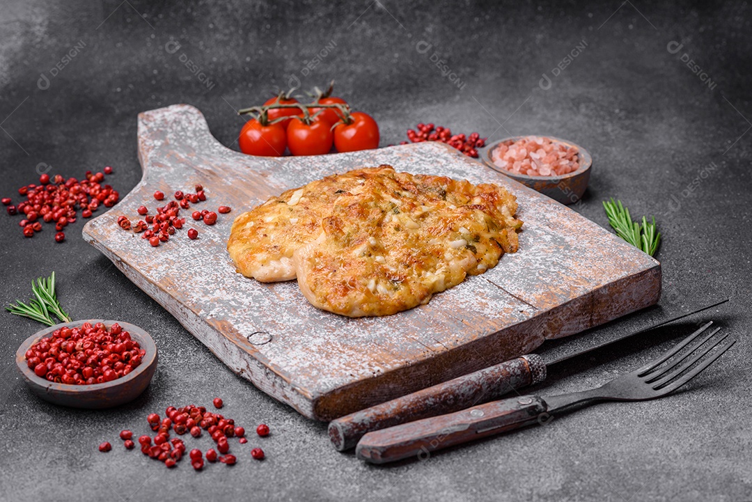 Delicioso peito de frango frito em massa com mostarda, sal, especiarias e queijo sobre fundo escuro de concreto