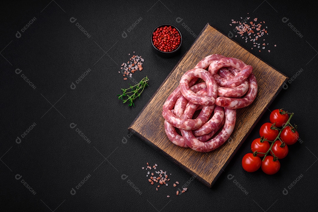 Salsichas cruas de porco ou vaca com sal, especiarias e ervas sobre um fundo escuro de concreto