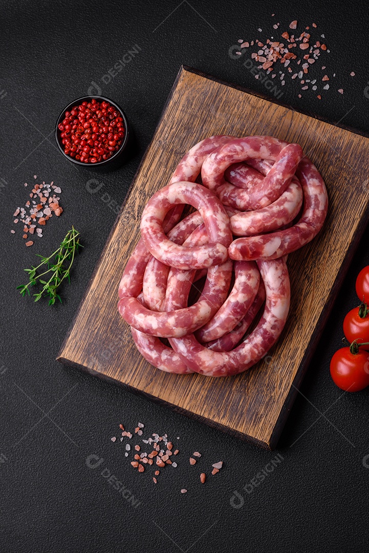 Salsichas cruas de porco ou vaca com sal, especiarias e ervas sobre um fundo escuro de concreto