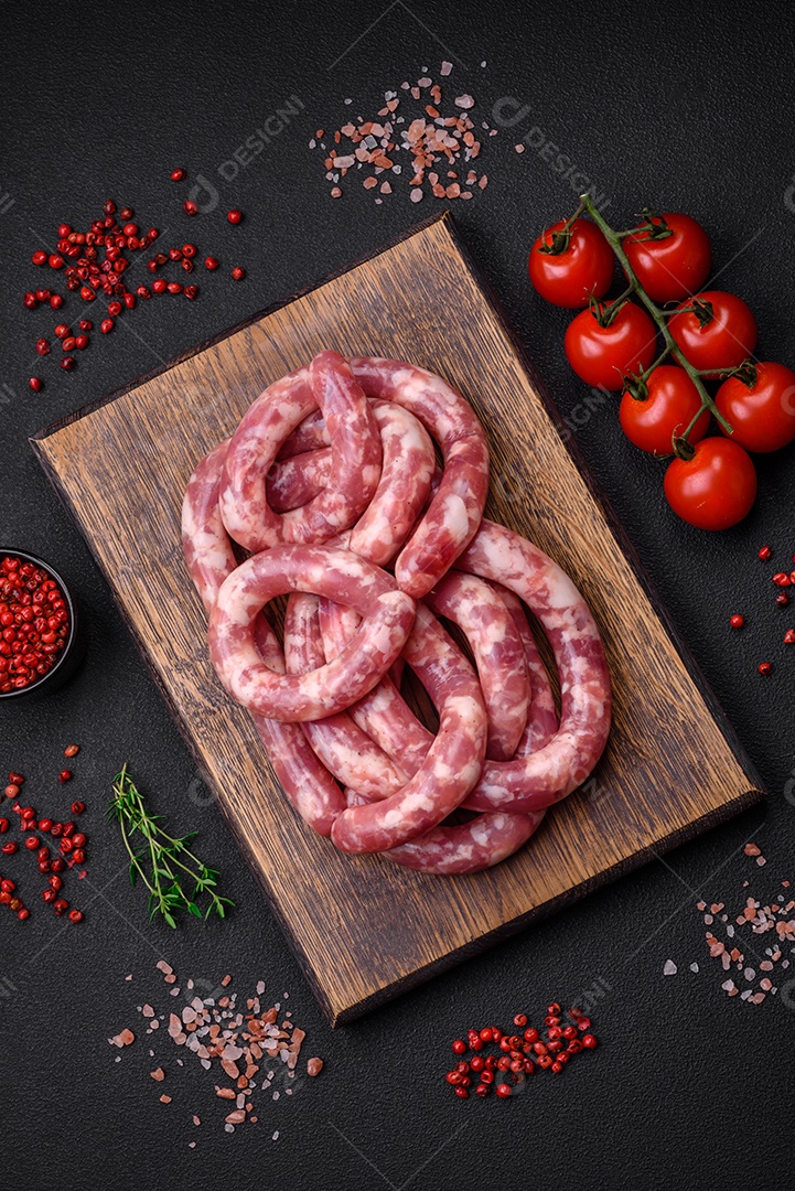 Salsichas cruas de porco ou vaca com sal, especiarias e ervas sobre um fundo escuro de concreto