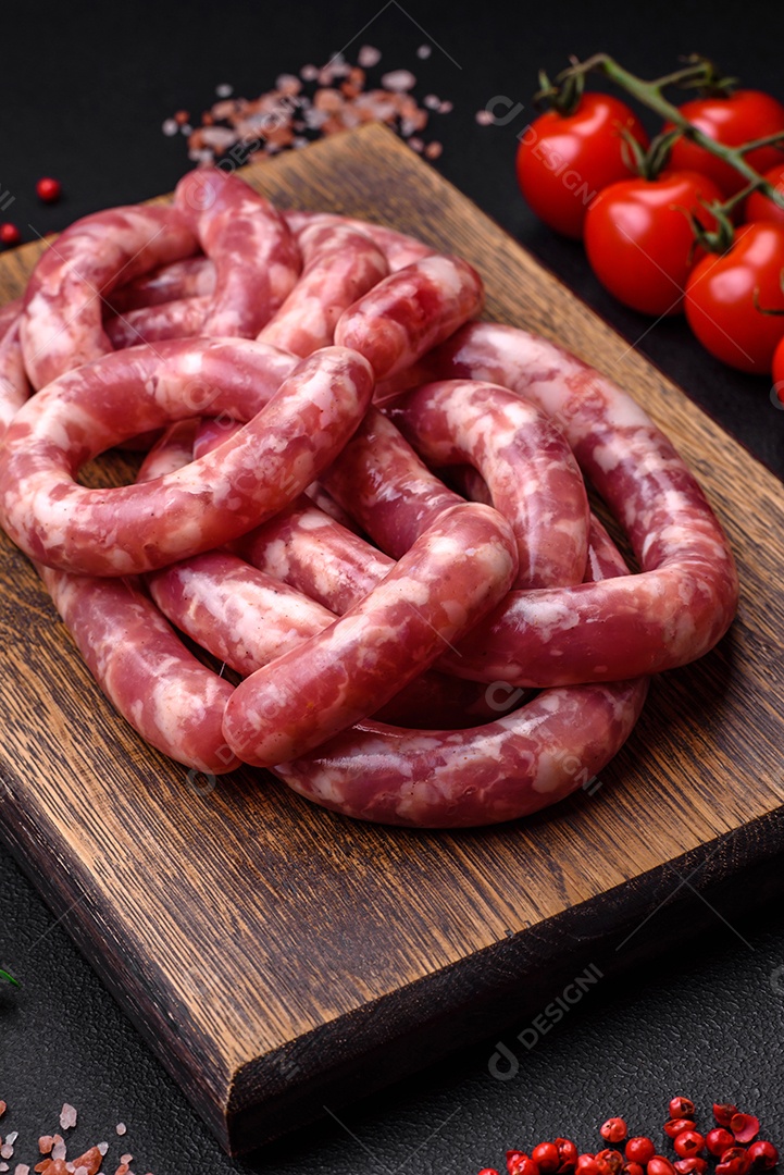 Salsichas cruas de porco ou vaca com sal, especiarias e ervas sobre um fundo escuro de concreto