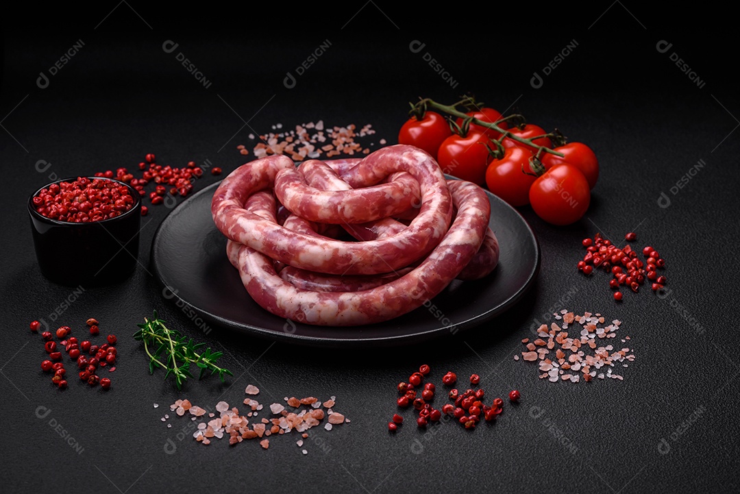 Salsichas cruas de porco ou vaca com sal, especiarias e ervas sobre um fundo escuro de concreto