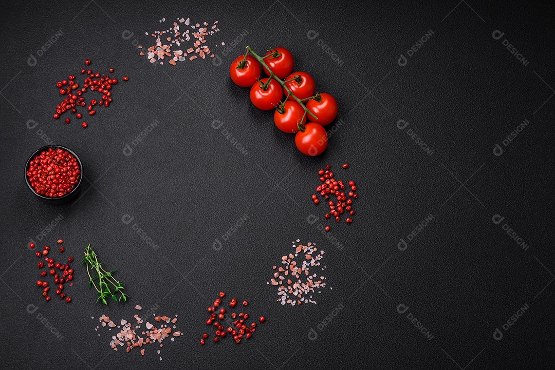 Ingredientes para cozinhar tomate cereja, sal, especiarias e ervas sobre um fundo escuro de concreto