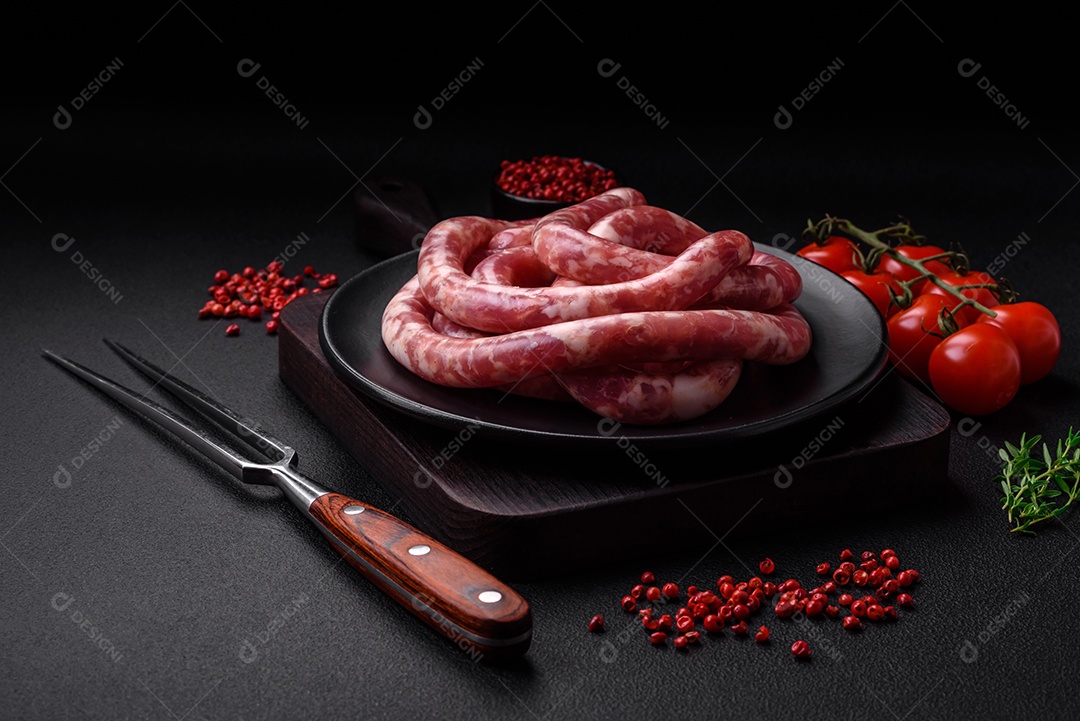 Salsichas cruas de porco ou vaca com sal, especiarias e ervas sobre um fundo escuro de concreto