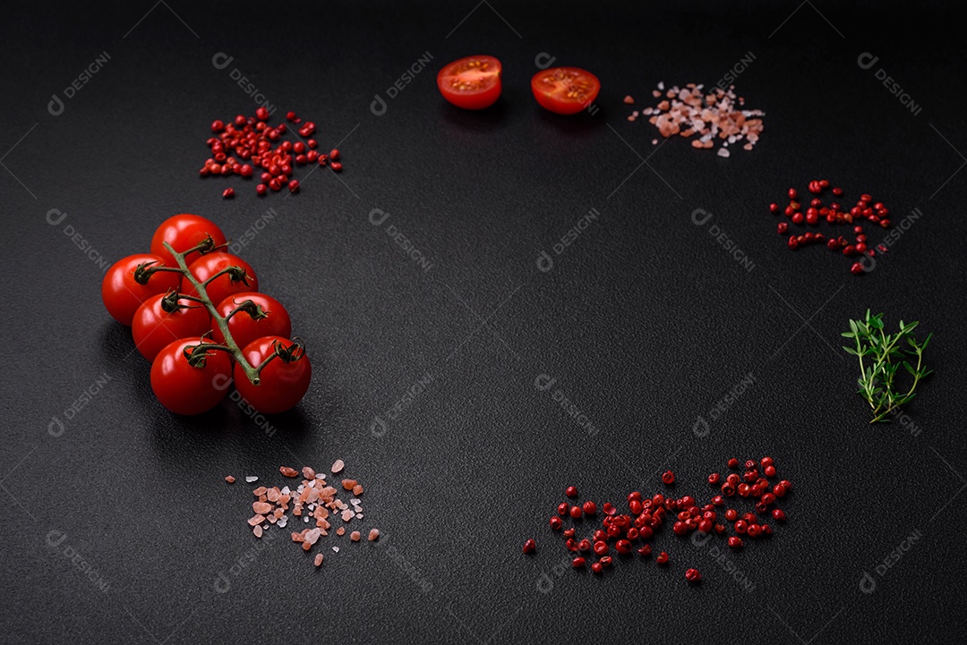 Ingredientes para cozinhar tomate cereja, sal, especiarias e ervas sobre um fundo escuro de concreto