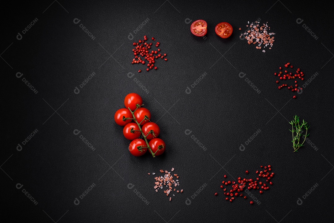 Ingredientes para cozinhar tomate cereja, sal, especiarias e ervas sobre um fundo escuro de concreto