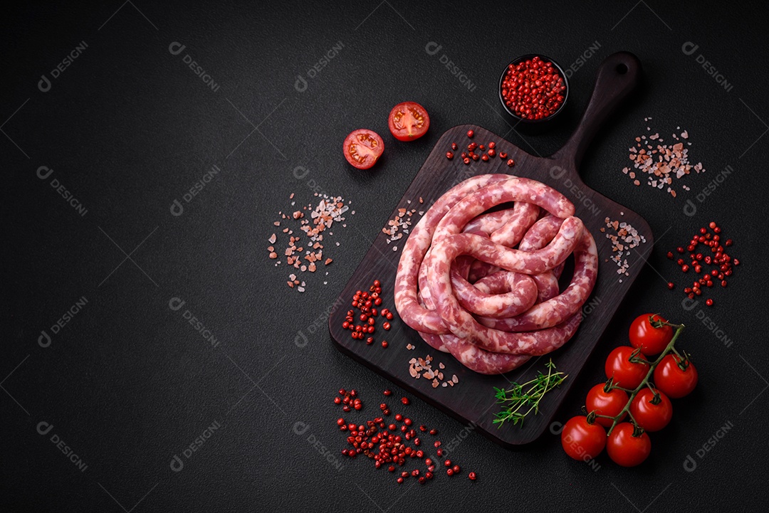 Salsichas cruas de porco ou vaca com sal, especiarias e ervas sobre um fundo escuro de concreto