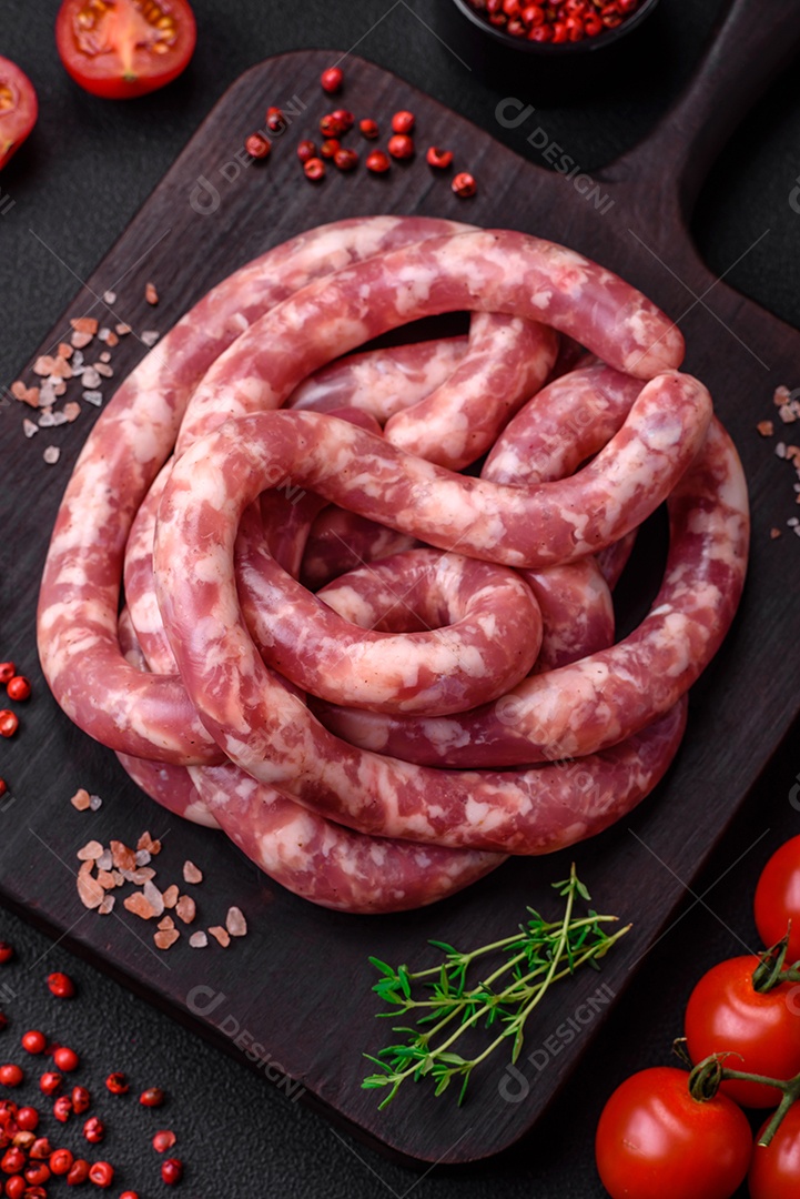 Salsichas cruas de porco ou vaca com sal, especiarias e ervas sobre um fundo escuro de concreto