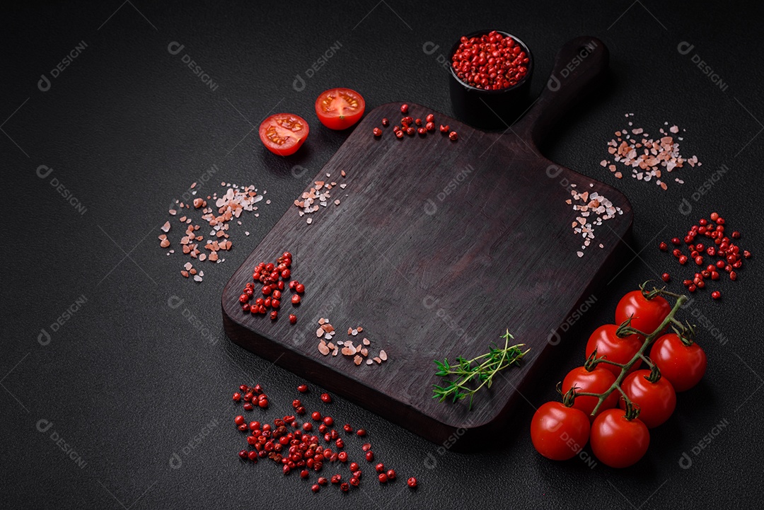 Ingredientes para cozinhar tomate cereja, sal, especiarias e ervas sobre um fundo escuro de concreto