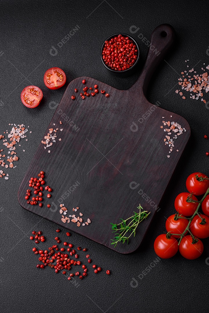 Ingredientes para cozinhar tomate cereja, sal, especiarias e ervas sobre um fundo escuro de concreto