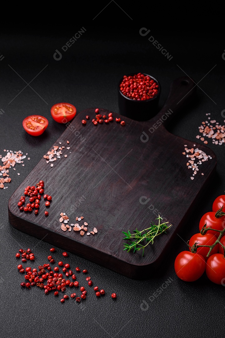 Ingredientes para cozinhar tomate cereja, sal, especiarias e ervas sobre um fundo escuro de concreto