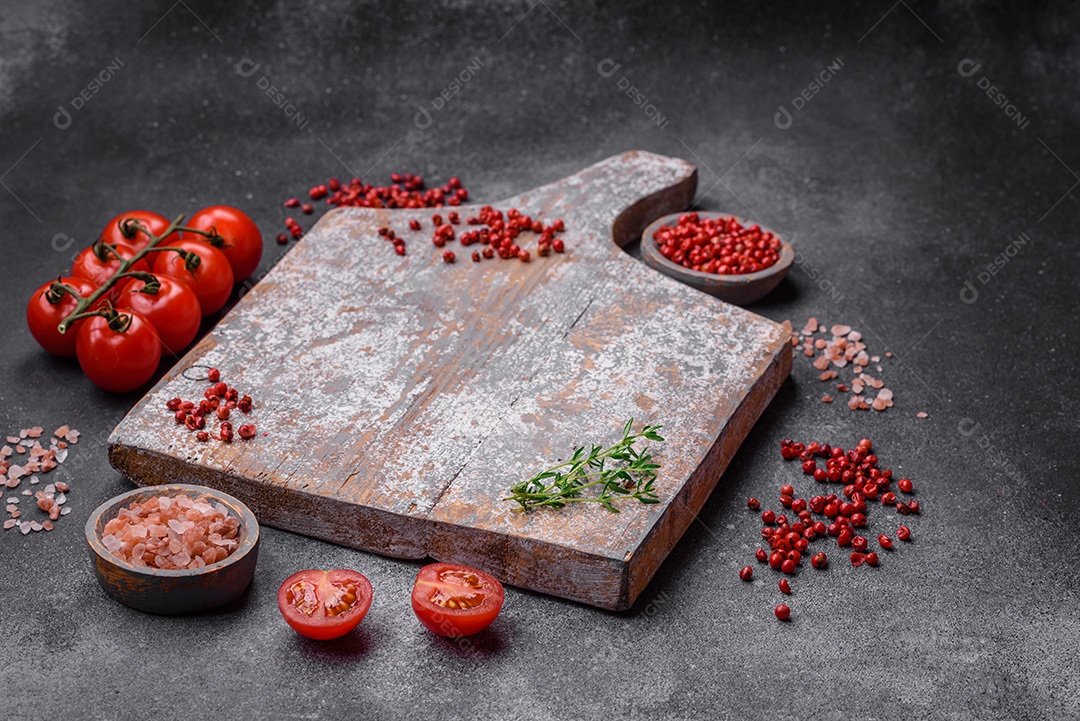 Ingredientes para cozinhar tomate cereja, sal, especiarias e ervas sobre um fundo escuro de concreto