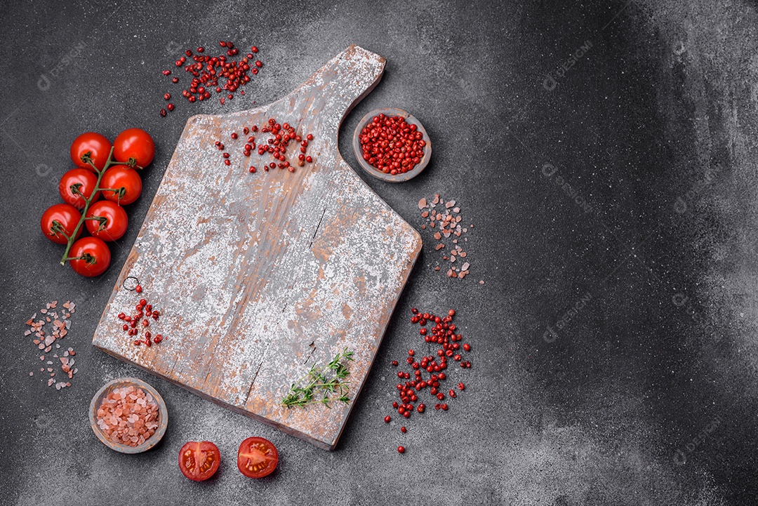 Ingredientes para cozinhar tomate cereja, sal, especiarias e ervas sobre um fundo escuro de concreto