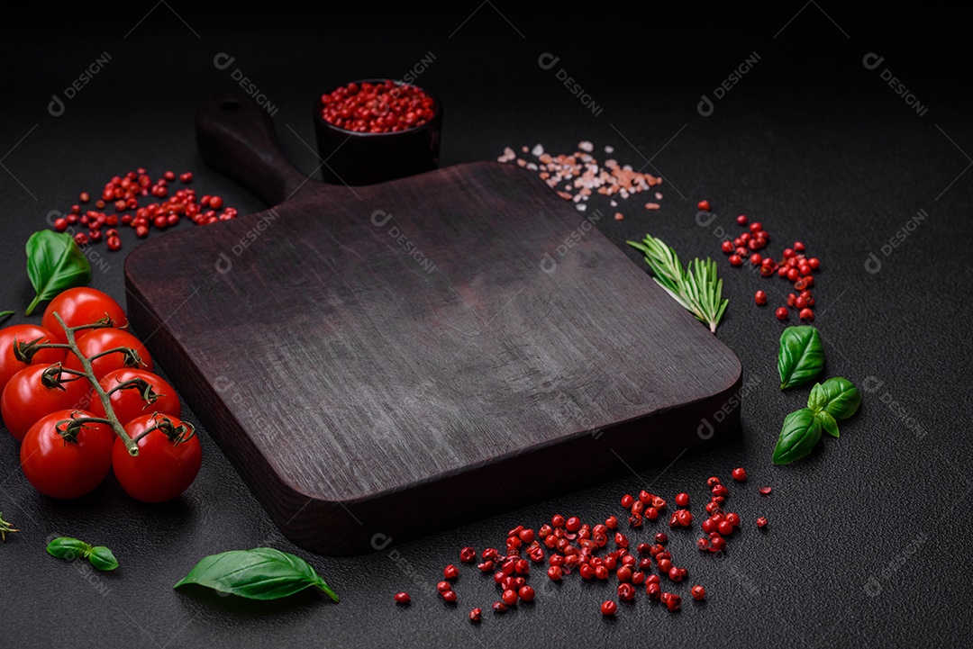 Ingredientes para cozinhar tomate cereja, sal, especiarias e ervas sobre um fundo escuro de concreto