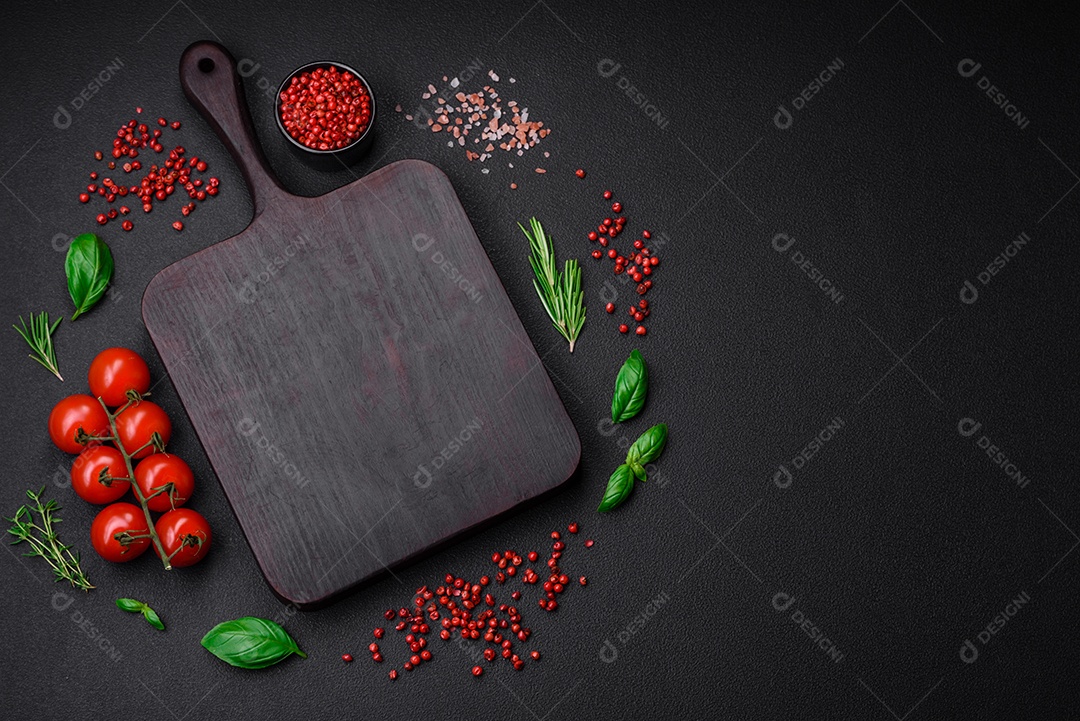 Ingredientes para cozinhar tomate cereja, sal, especiarias e ervas sobre um fundo escuro de concreto