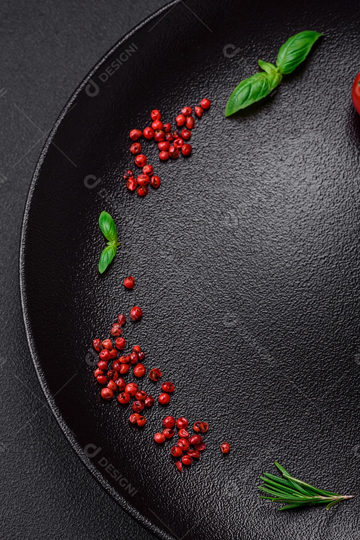 Ingredientes para cozinhar tomate cereja, sal, especiarias e ervas sobre um fundo escuro de concreto