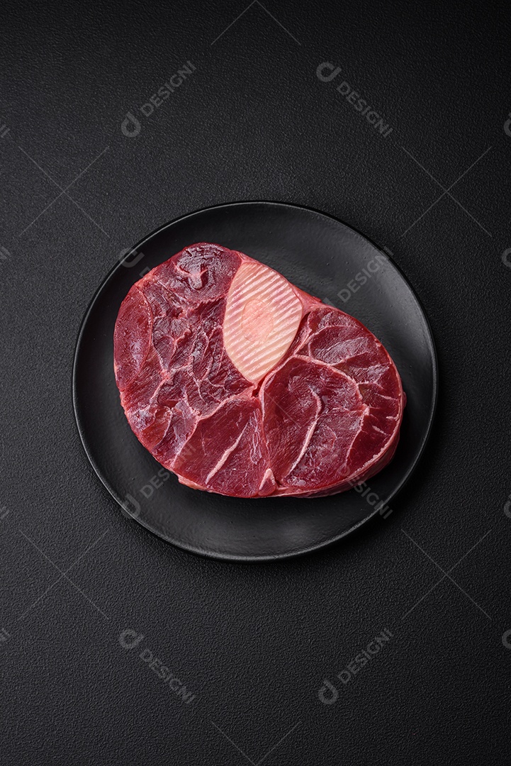 Bife de ossobuco de carne fresca com sal, especiarias e ervas em fundo de concreto texturizado