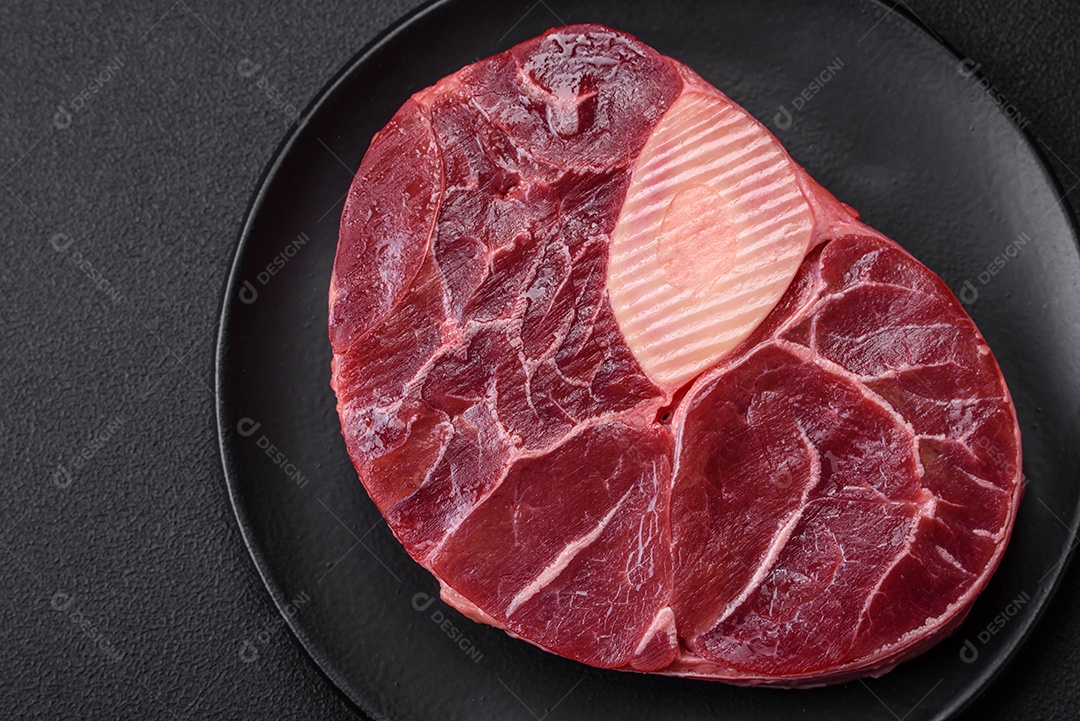Bife de ossobuco de carne fresca com sal, especiarias e ervas em fundo de concreto texturizado