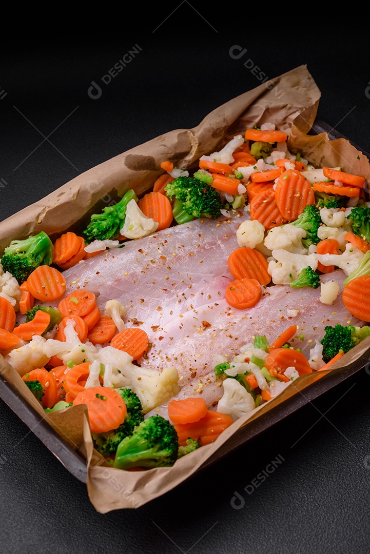 Filé de peixe robalo cru com sal, especiarias e legumes em uma assadeira sobre um fundo texturizado