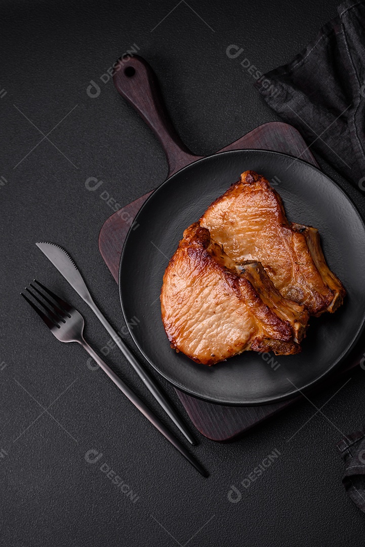 Delicioso suculento bife de porco ou de vaca com sal, especiarias e ervas sobre um fundo de concreto texturizado