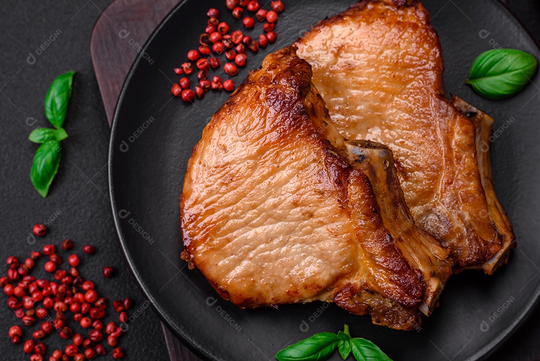 Delicioso suculento bife de porco ou de vaca com sal, especiarias e ervas sobre um fundo de concreto texturizado