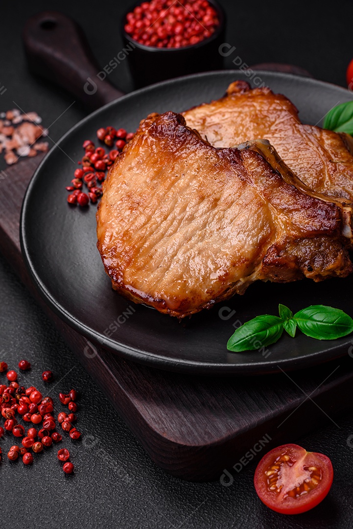 Delicioso suculento bife de porco ou de vaca com sal, especiarias e ervas sobre um fundo de concreto texturizado