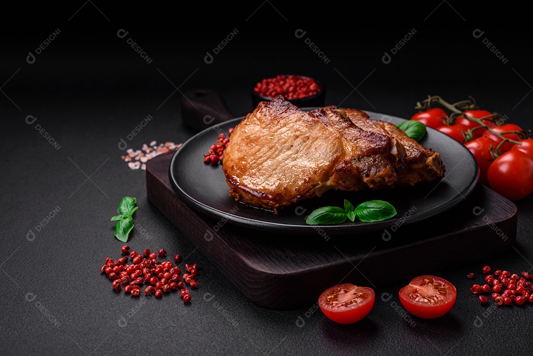 Delicioso suculento bife de porco ou de vaca com sal, especiarias e ervas sobre um fundo de concreto texturizado