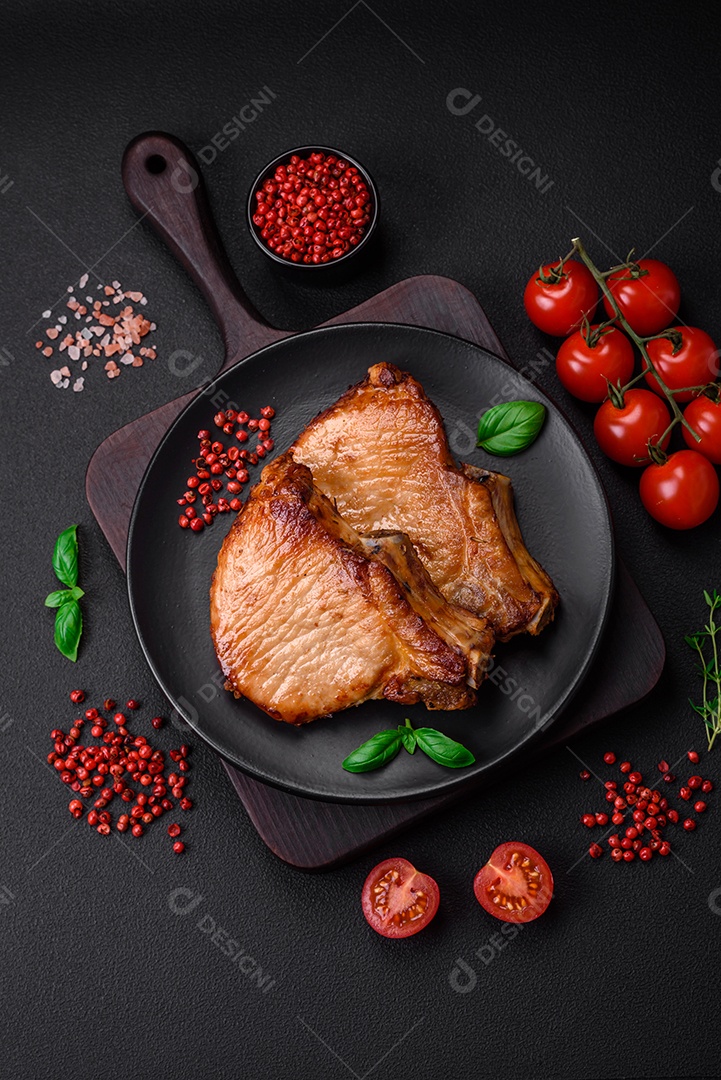 Delicioso suculento bife de porco ou de vaca com sal, especiarias e ervas sobre um fundo de concreto texturizado