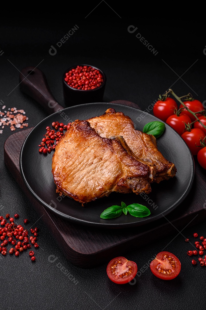 Delicioso suculento bife de porco ou de vaca com sal, especiarias e ervas sobre um fundo de concreto texturizado