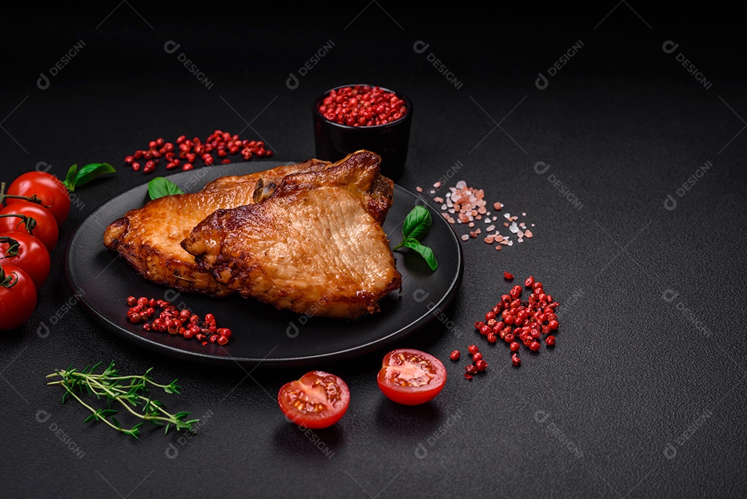 Delicioso suculento bife de porco ou de vaca com sal, especiarias e ervas sobre um fundo de concreto texturizado