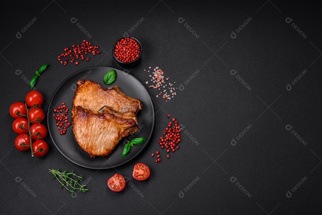 Delicioso suculento bife de porco ou de vaca com sal, especiarias e ervas sobre um fundo de concreto texturizado