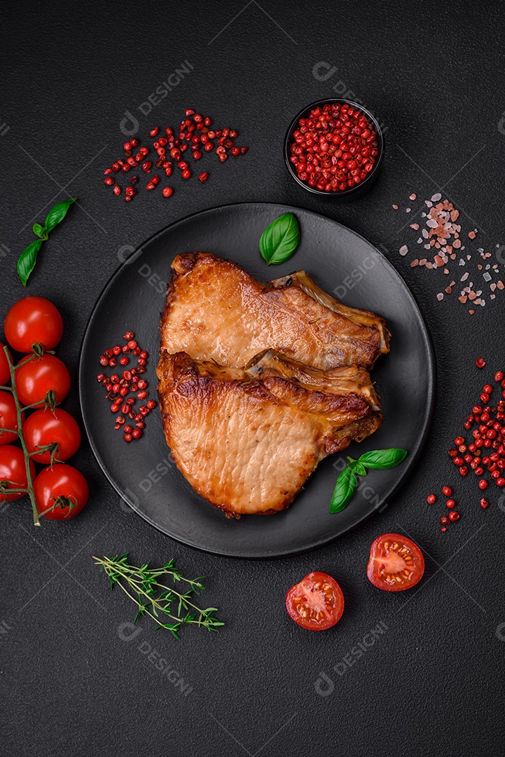 Delicioso suculento bife de porco ou de vaca com sal, especiarias e ervas sobre um fundo de concreto texturizado