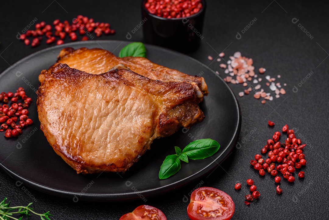 Delicioso suculento bife de porco ou de vaca com sal, especiarias e ervas sobre um fundo de concreto texturizado