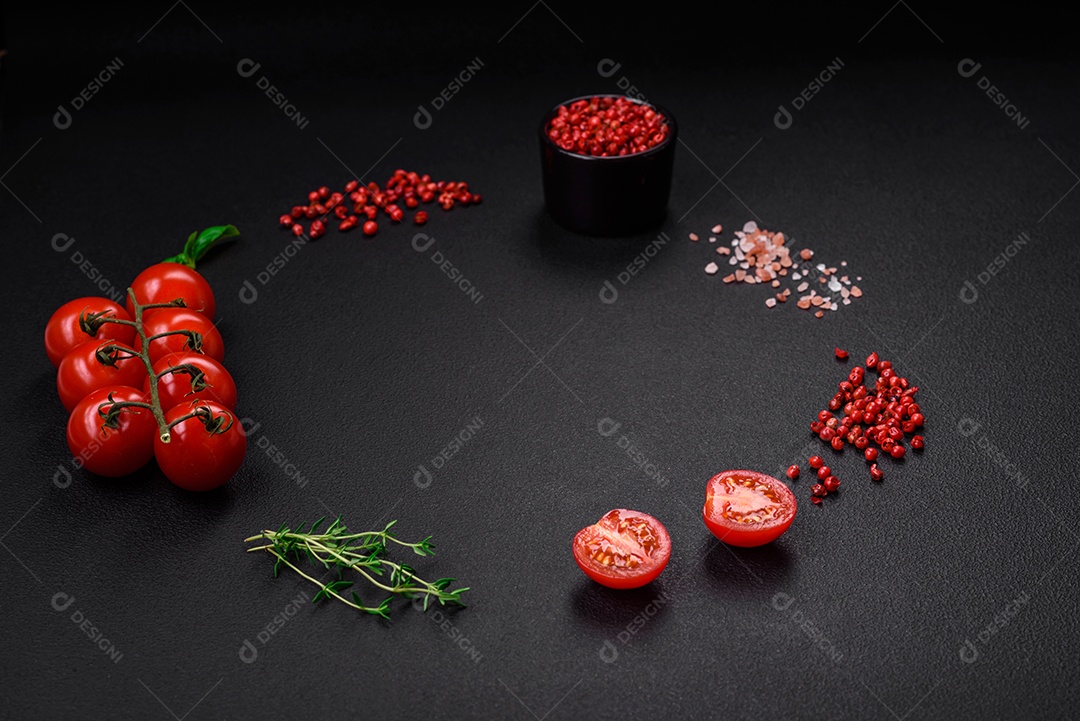 Ingredientes para cozinhar tomate cereja, sal, especiarias e ervas sobre um fundo escuro de concreto