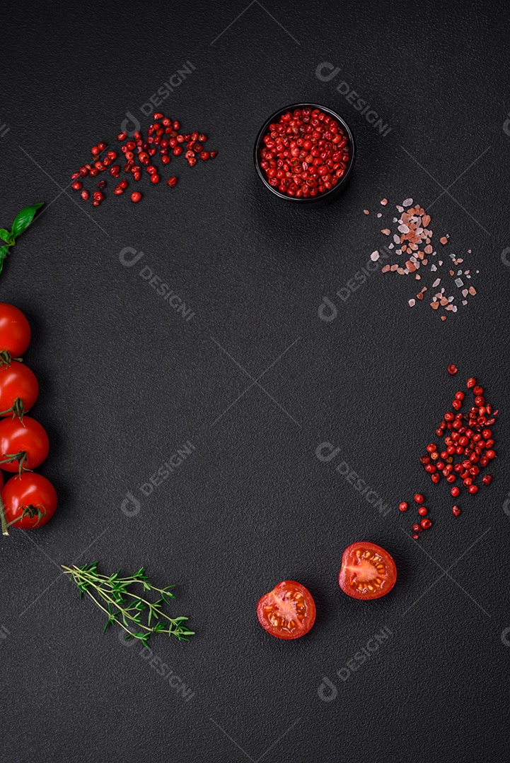 Ingredientes para cozinhar tomate cereja, sal, especiarias e ervas sobre um fundo escuro de concreto