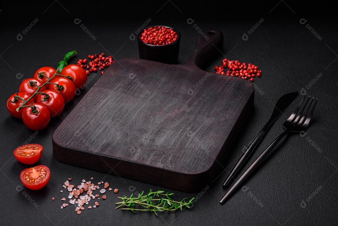 Ingredientes para cozinhar tomate cereja, sal, especiarias e ervas sobre um fundo escuro de concreto