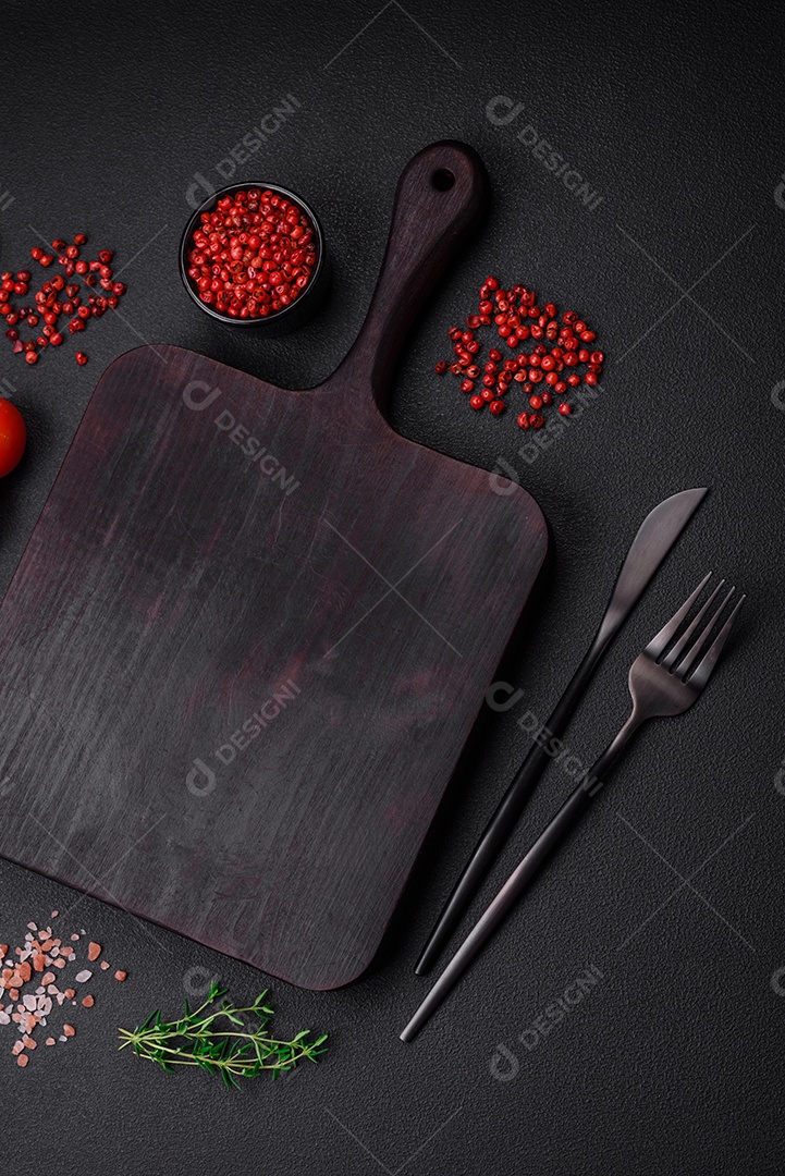 Ingredientes para cozinhar tomate cereja, sal, especiarias e ervas sobre um fundo escuro de concreto