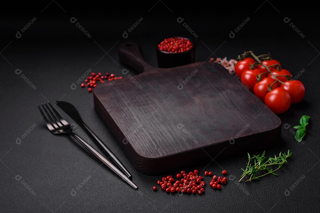 Ingredientes para cozinhar tomate cereja, sal, especiarias e ervas sobre um fundo escuro de concreto