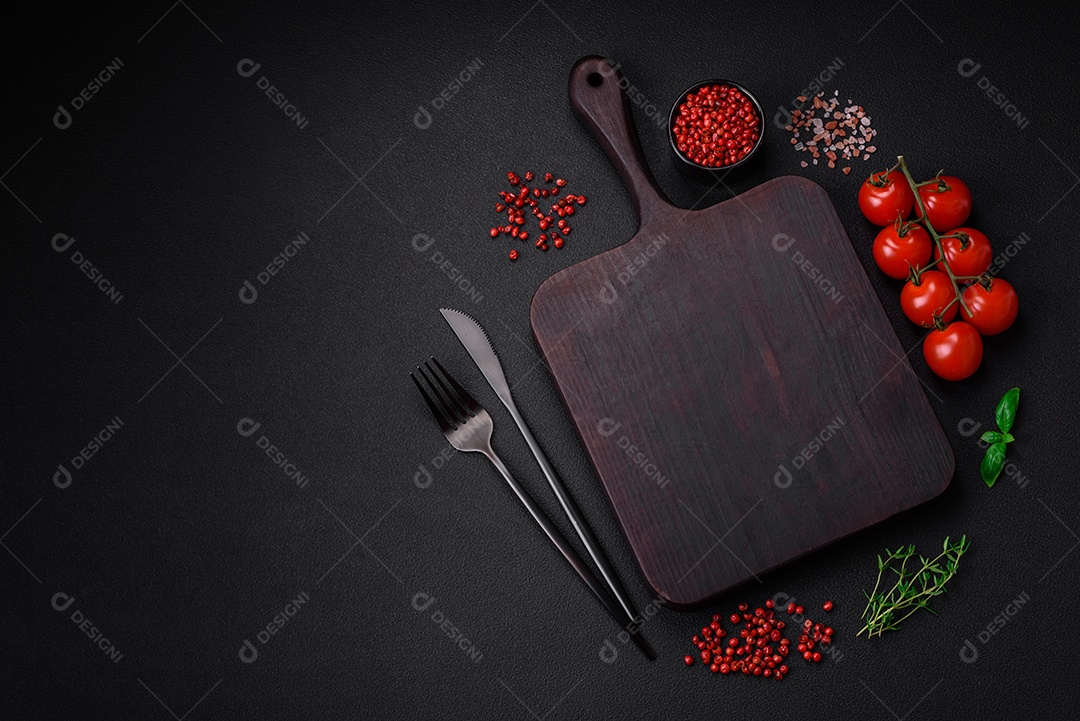 Ingredientes para cozinhar tomate cereja, sal, especiarias e ervas sobre um fundo escuro de concreto